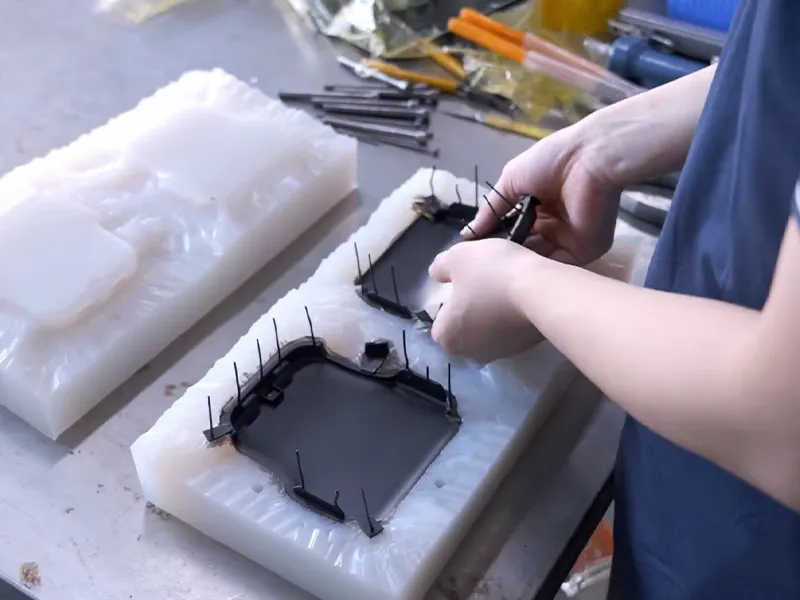 Technician demolding vacuum cast plastic parts from a silicone mold after curing