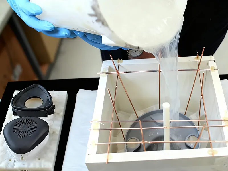 Liquid silicone pouring over a master pattern to create a vacuum casting mold