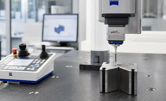 Coordinate measuring machine probe positioned above a metal component on a measurement table.